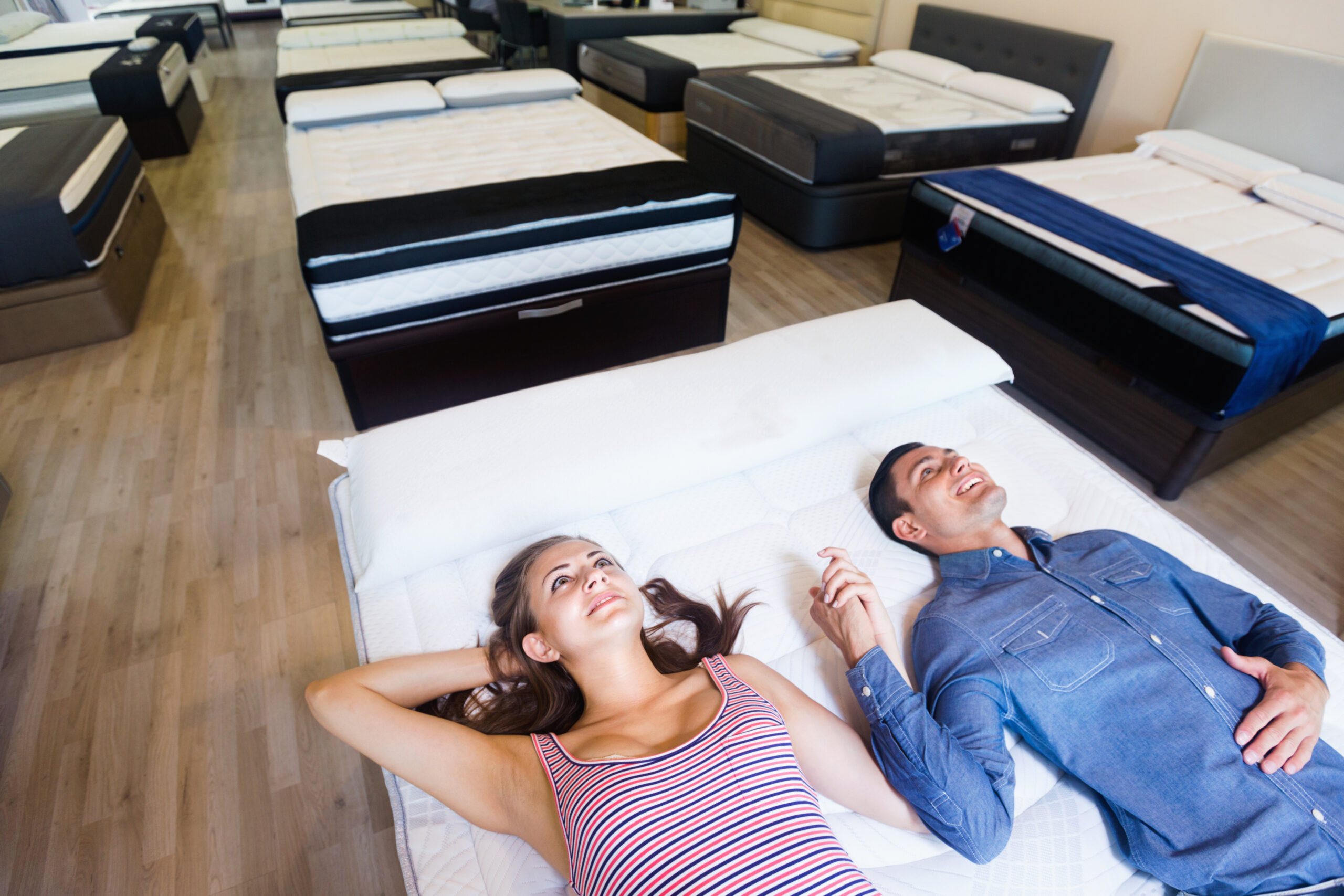 A couple trying out mattresses in a local mattress store. 